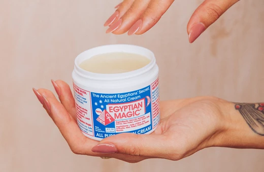 Crema mágica antiarrugas Egyptian Magic manos de mujer sujetando un bote abierto de crema Egyptian Magic