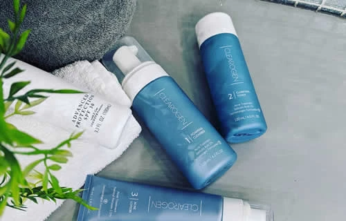 Tres ampolles de productes per a la cura de la pell sobre una taula, representant la línia Clearogen i el seu enfocament científic.