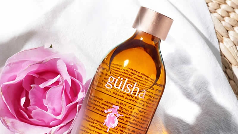 Aceite de rosa glamuroso Gulsha en un frasco elegante, con un fondo suave que resalta su color y textura lujosa