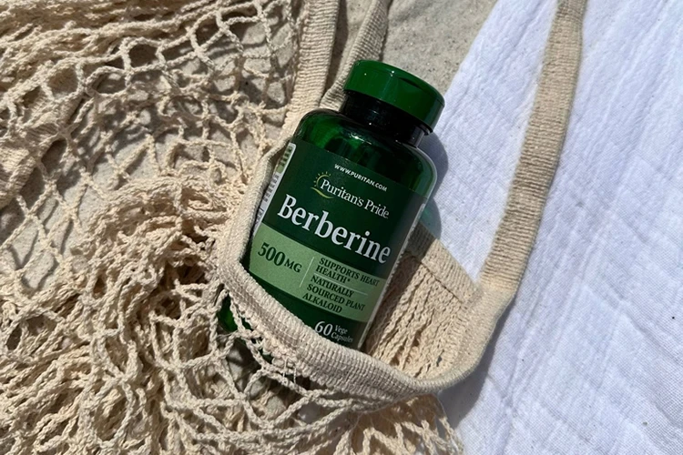Puritan's Pride Berberine suplement Frasco de barberina de Puritan's Pride en una bolsa sobre la arena de una playa.