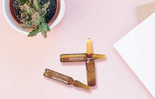 Ampolla de sèrum de vitamina C al costat d’una planta, simbolitzant la cura i la salut de la pell