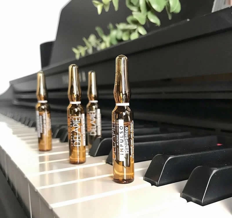 Tres ampolles Delapiel sobre un piano, simbolitzant innovació i eficàcia en la cura de la pell
