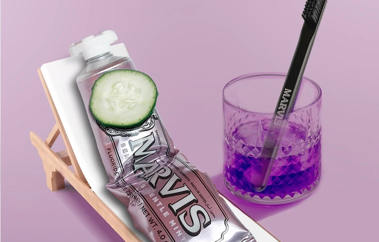 un tubo de pasta de dientes MARVIS metaforicamente humanizado tomando el sol en una hamaca con un vaso y un cipillo simulando un refresco