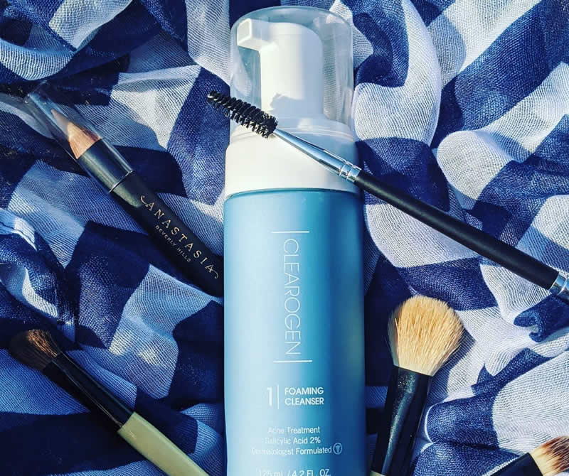 Frasco de limpiador, cepillo y brocha de maquillaje, elementos esenciales para una piel clara y saludable con Clearogen