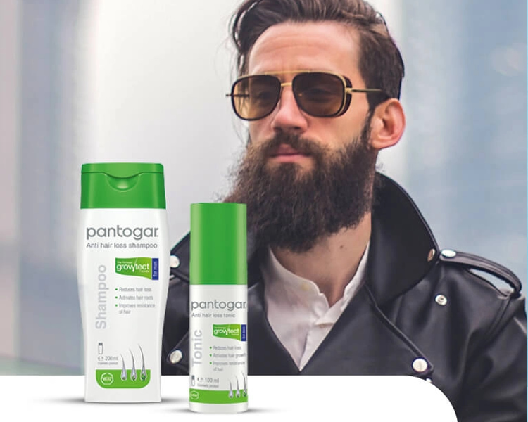 Hombre con hermoso cabello y barba y un producto pantogar champu en primer palno
